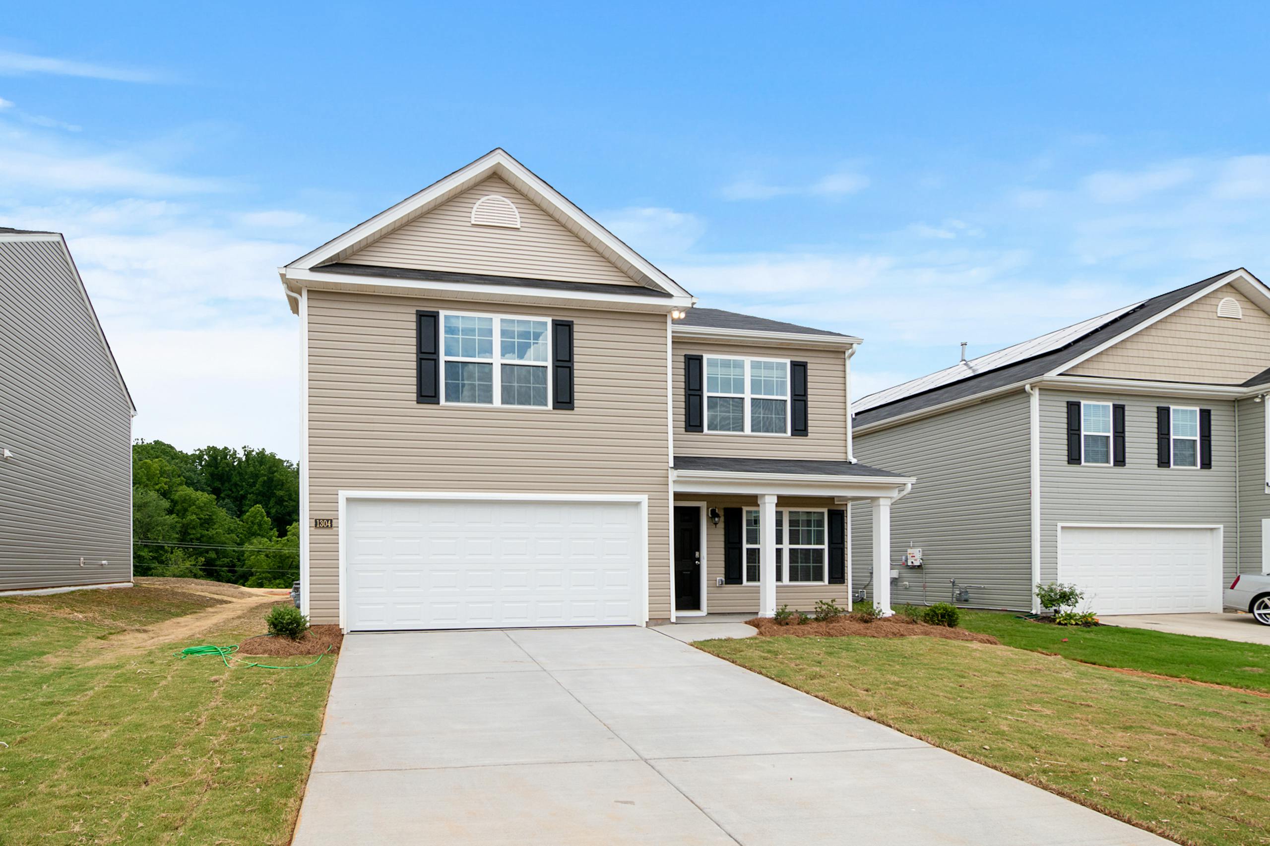 Contemporary two-story suburban home with a spacious driveway and lawn.